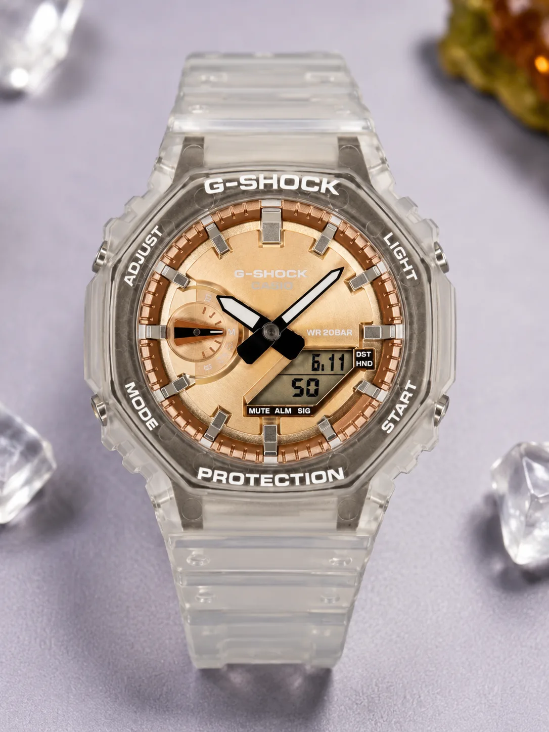 GA-2100BM, de face : boîtier en résine transparente givrée, cadran champagne cuivré, index appliqués argentés, aiguilles blanches et noires.