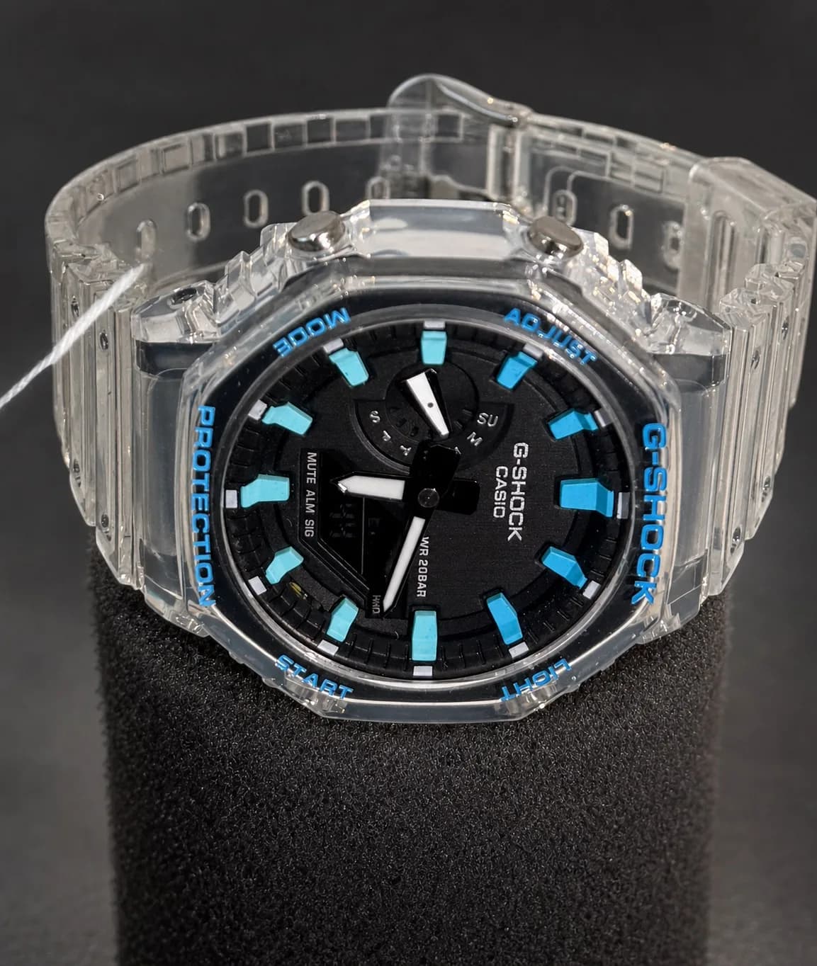 La même montre de trois quarts : épaisseur du boîtier transparent et attache du bracelet.