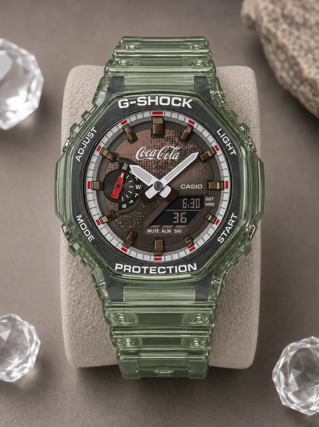 GA-2100CC-3AER, de face : boîtier en résine translucide vert fumé, cadran brun à motif imprimé, logo Coca-Cola rouge au centre, aiguille des secondes rouge.