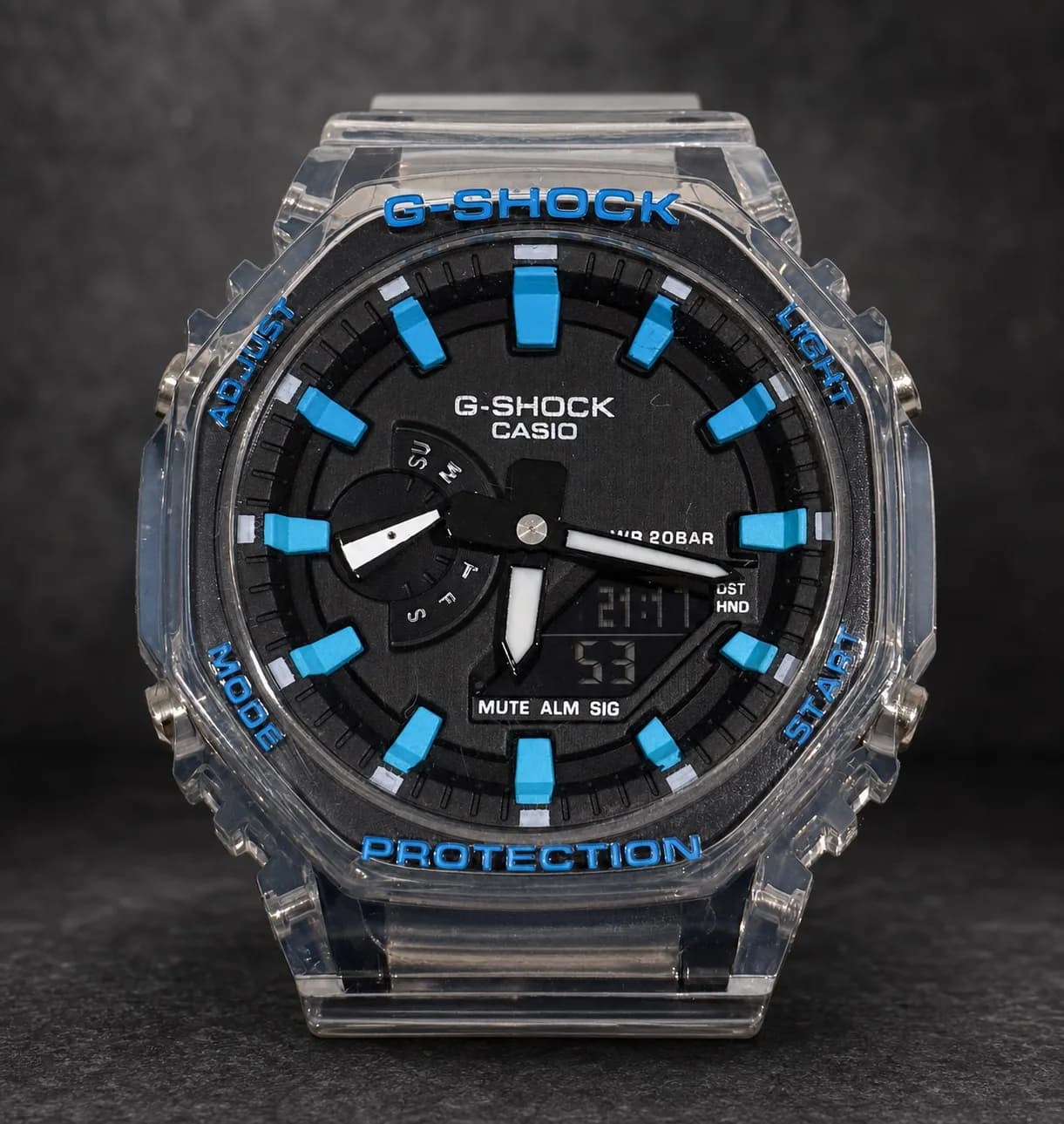 GA-2100TLS-8AJF de face : cadran noir, index et inscriptions bleus, boîtier en résine transparente.